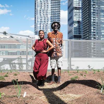 Nicole & Anan stand in the rooftop garden of Toronto Metropolitan University, with towering condos in the background