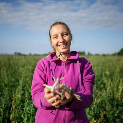 Smiling person in field holding beans